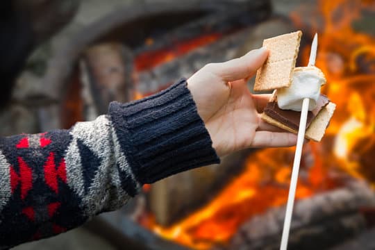 Holding a s’more near a campfire